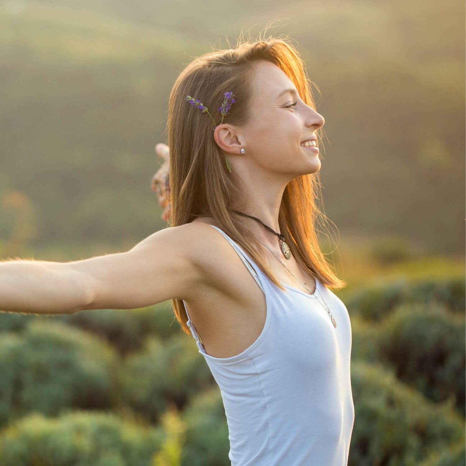 A woman enjoying nature with her arms outstretched in a sunlit environment, embodying a sense of freedom.