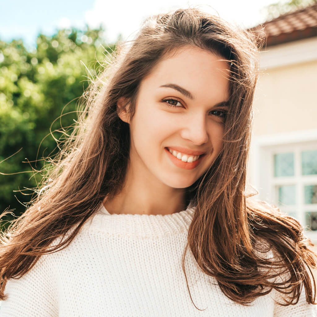 Happy woman smiling outdoors with long hair, showcasing a radiant and polished look using Japanese Nano Refreshing Liquid.