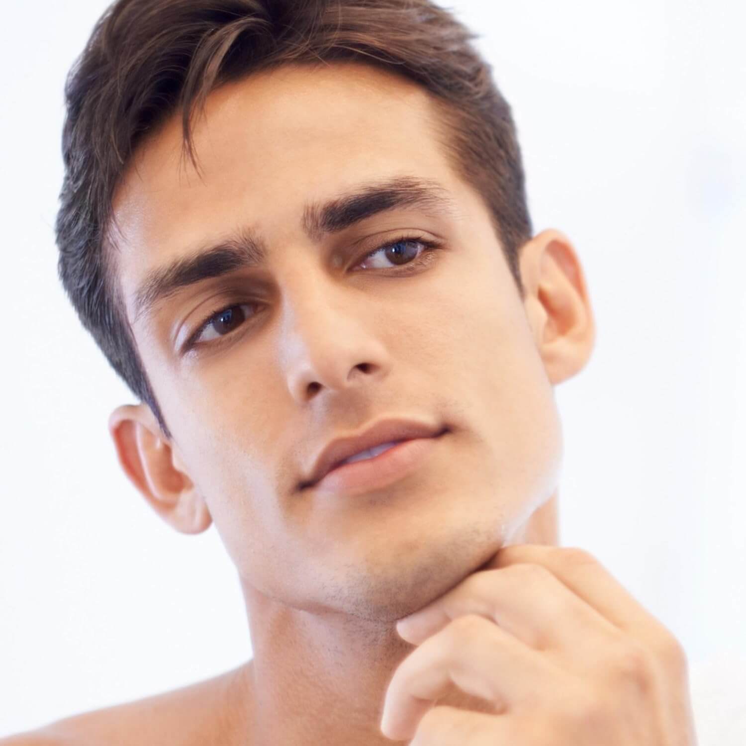 A young man with a smooth face contemplating, representing the benefits of Revibe Zen Cooling Shave Cream.